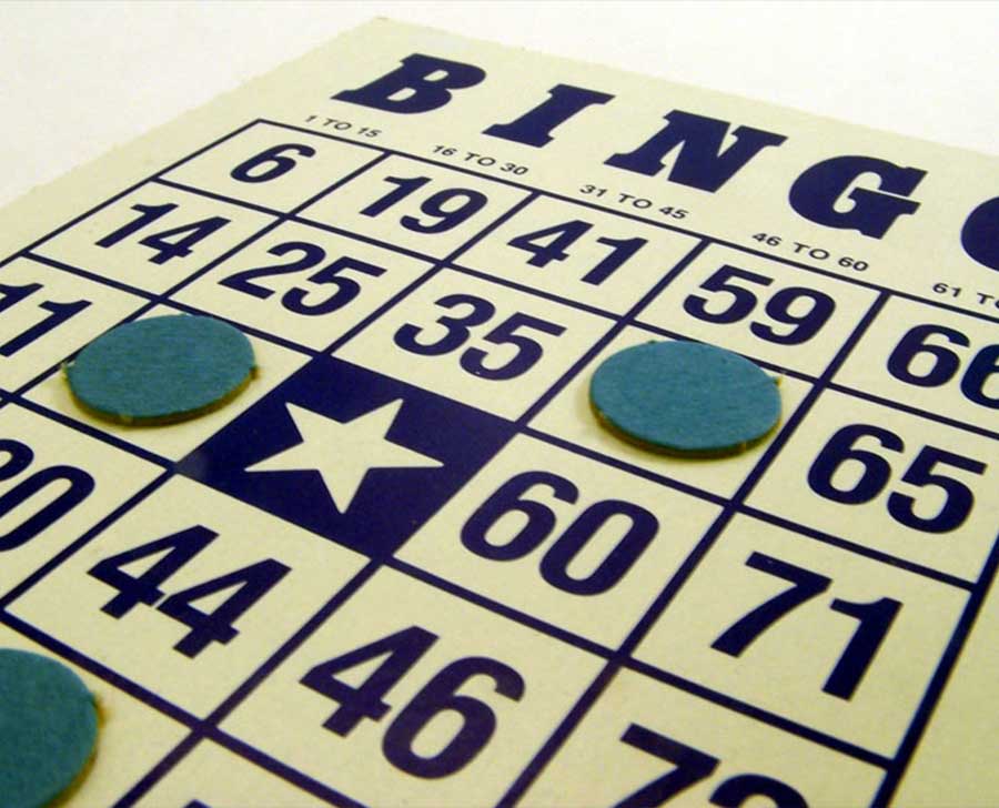 A close-up of a Bingo card with green markers covering several numbers and the free space.